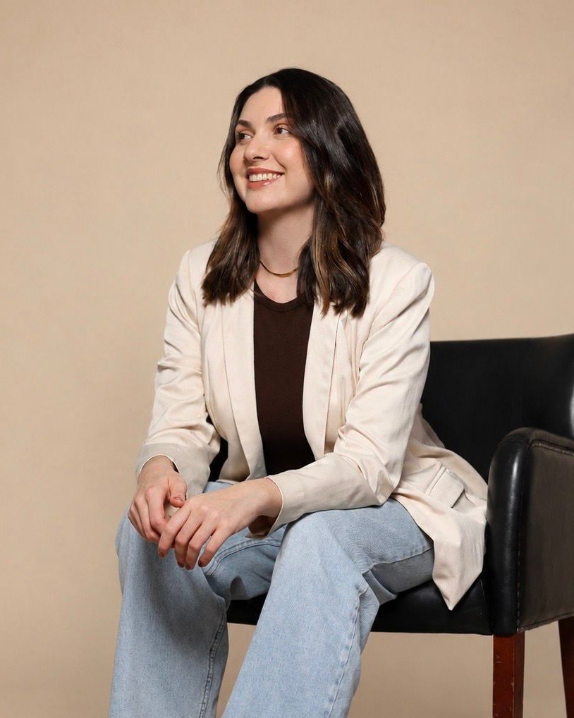 Juliane Balbueno, psicóloga, sentada e sorrindo