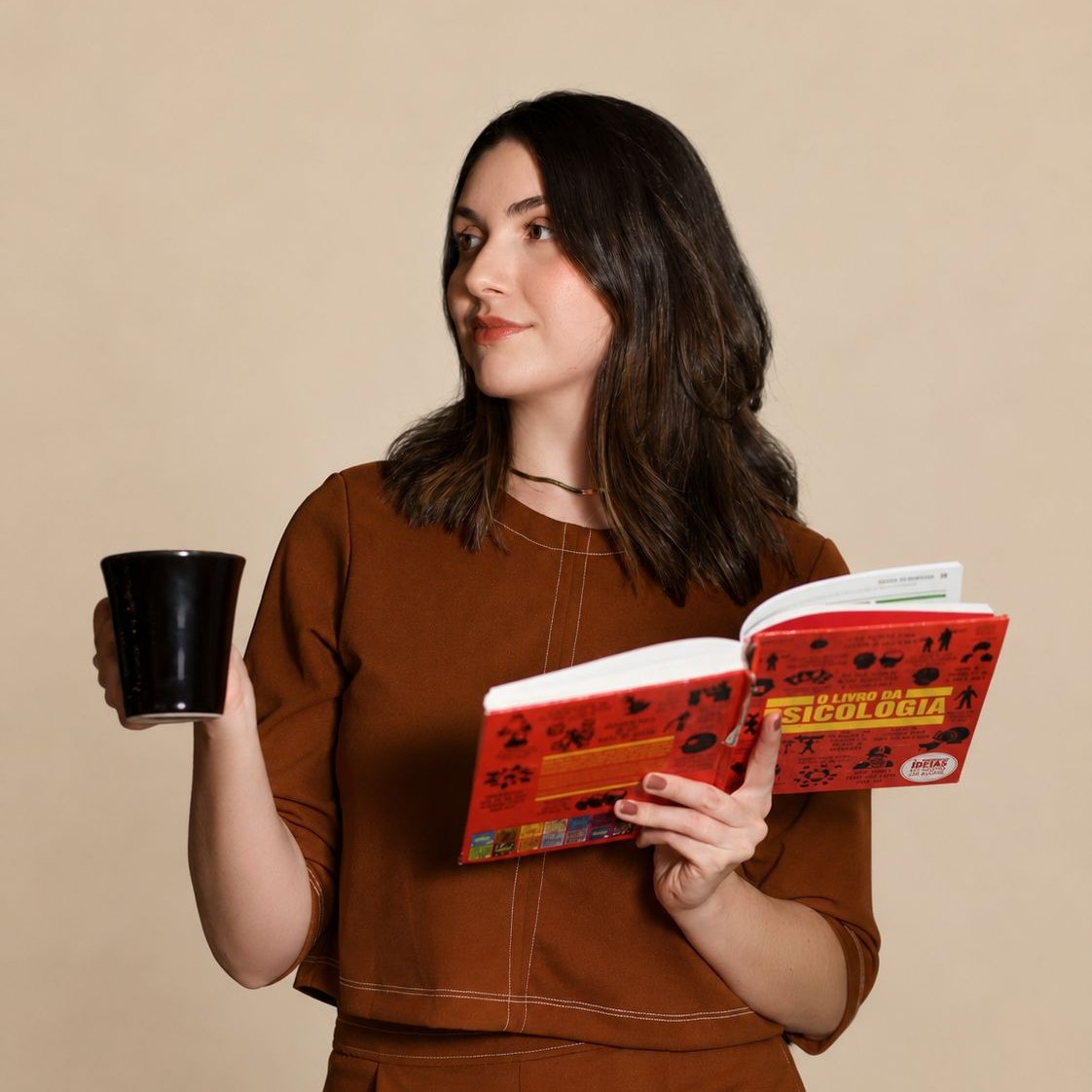 Juliane Balbueno segurando O Livro da Psicologia e uma caneca