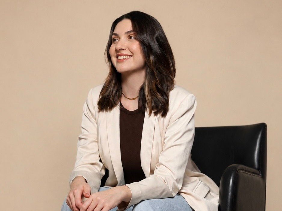Juliane Balbueno sorrindo, sentada em uma cadeira